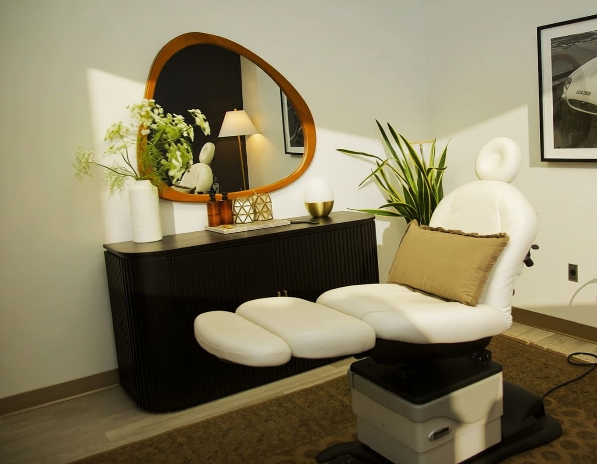 SKINHAUS treatment room with white chair, mirror, and plants